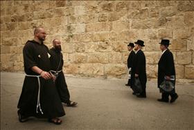 Ultra-Orthodox men pass by Christian Monks in Jerusalem's Old City.  Credit Miriam Alister, Flash 90