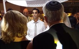 Tzachi under the chuppah with Sara's parents watching in the foreground